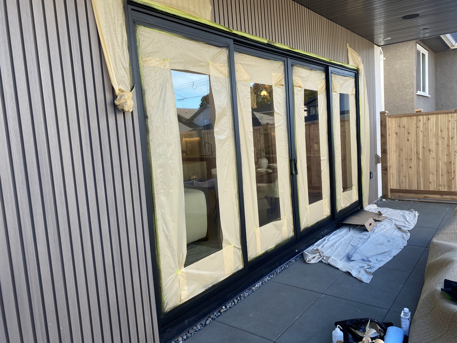 Four-panel patio door with the glass masked off while the black frames are refinished