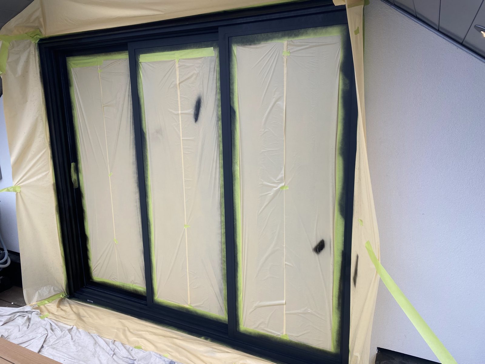 Three-panel sliding door masked off with fresh black finish on the frames