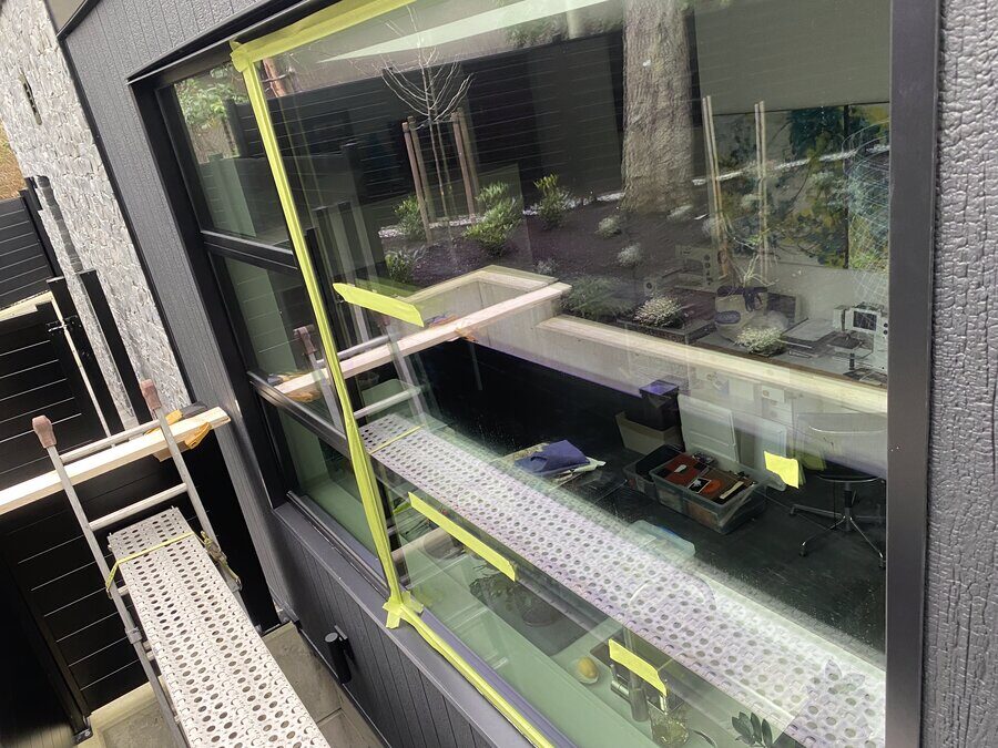 Large window with scratches marked out in tape before polishing