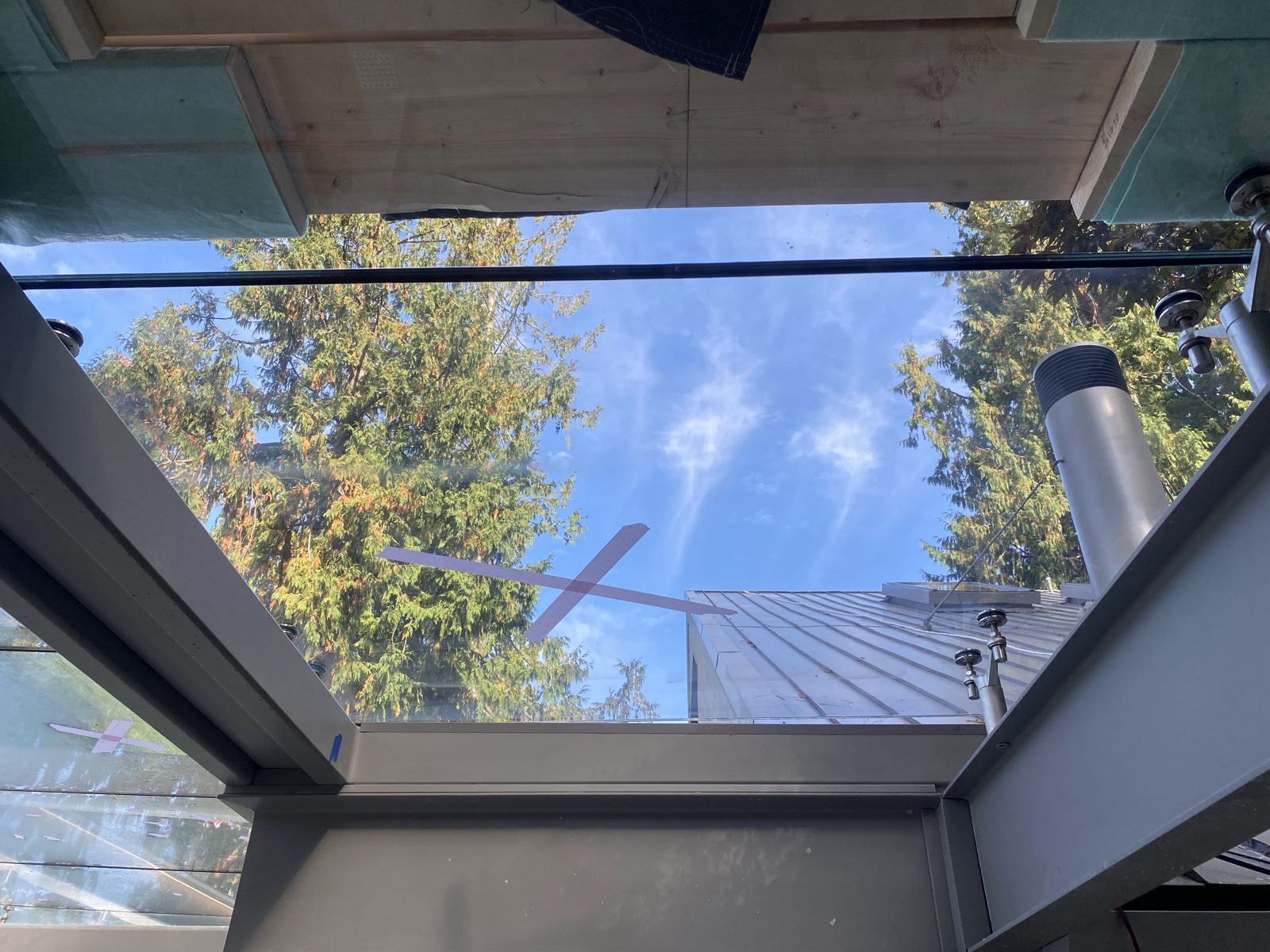 Canopy glass panel with scratches taped off, framed by steel beams